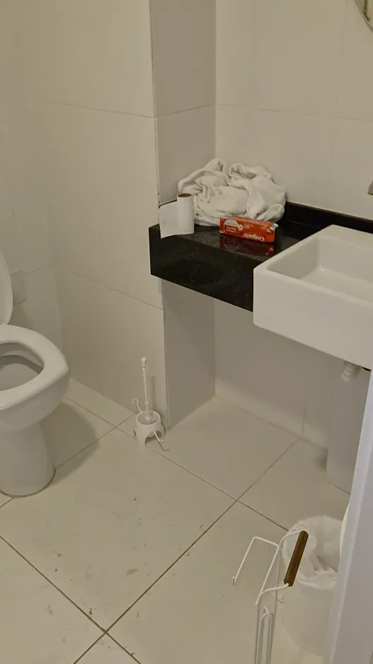 Banheiro do apartamento na manhã seguinte, com toalhas usadas e piso sujo